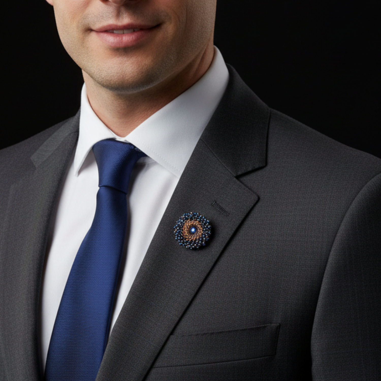 Man wearing a gray suit with a blue tie and decorative lapel pin against a black background