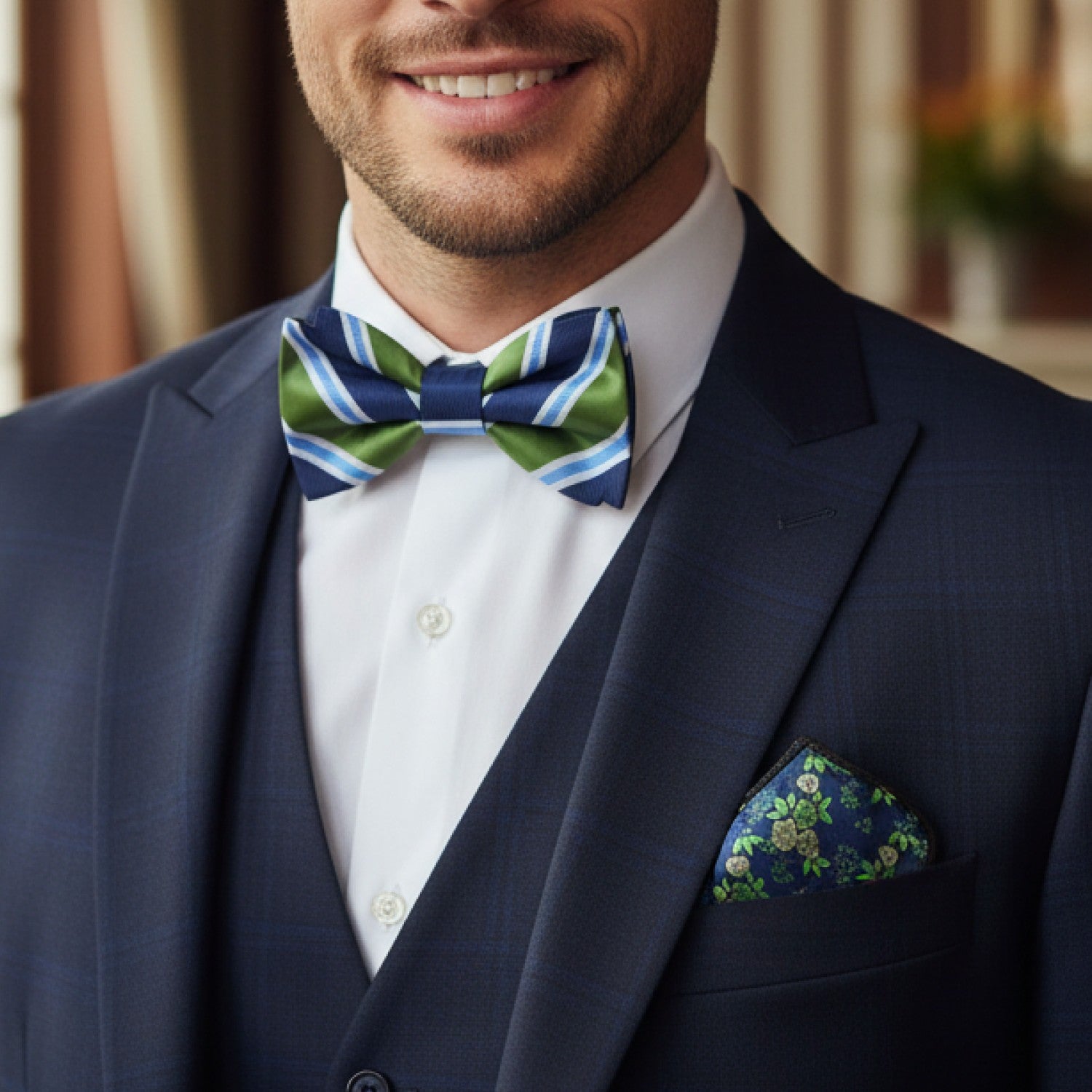 Man wearing a navy suit with a striped green and blue bow tie and floral pocket square.