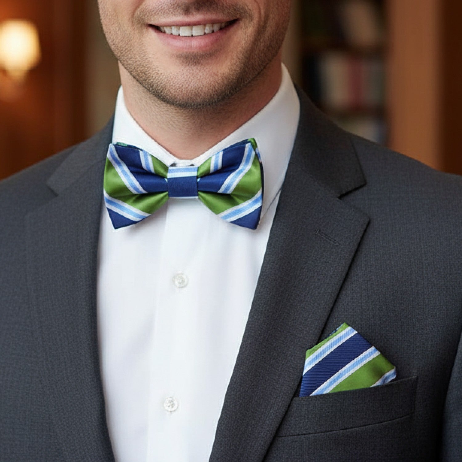 Man wearing a gray suit with a striped green and blue bow tie and pocket square.