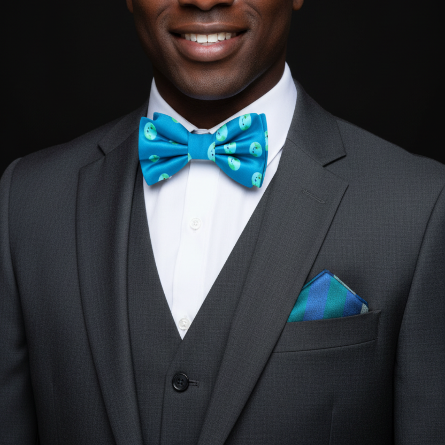 Man wearing a gray suit with a blue bow tie and pocket square on a black background