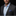 Man wearing a dark suit with a blue shirt and patterned pocket square on a black background