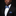 Man wearing a black suit with a white shirt and blue patterned bow tie and pocket square against a black background