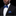 Man wearing a black suit with a blue polka dot bow tie and pocket square on a black background