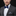 Man wearing a gray suit with a white shirt and blue bow tie on a black background