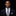 Man wearing a black suit with a white shirt and gray tie on a black background