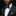 Man wearing a black suit with a blue bow tie and pocket square on a black background