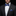 Man wearing a black suit with a blue checkered bow tie and pocket square against a dark background