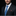 Man wearing a dark suit with a blue tie and patterned pocket square on a black background