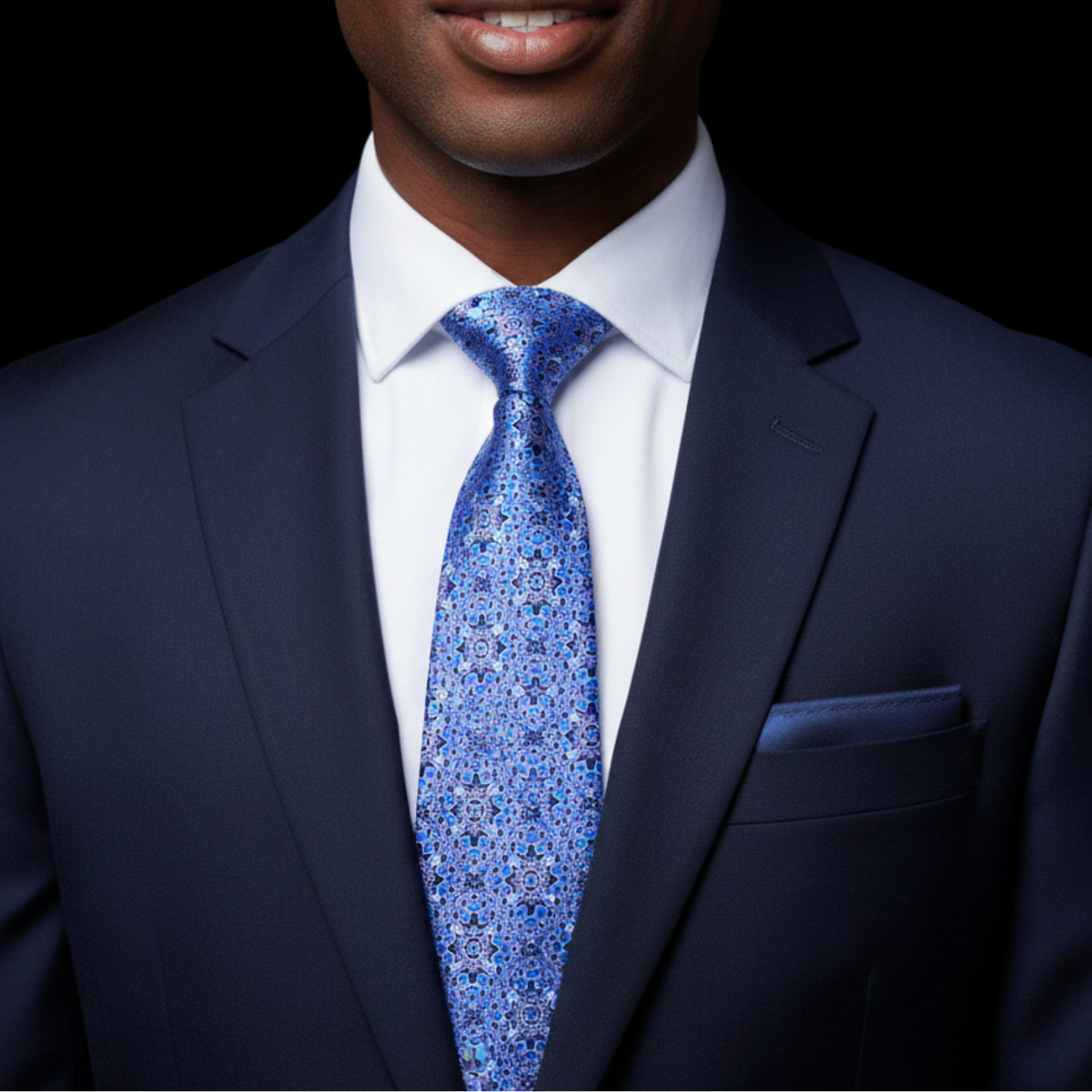 Man wearing a navy suit with a blue patterned tie on a black background