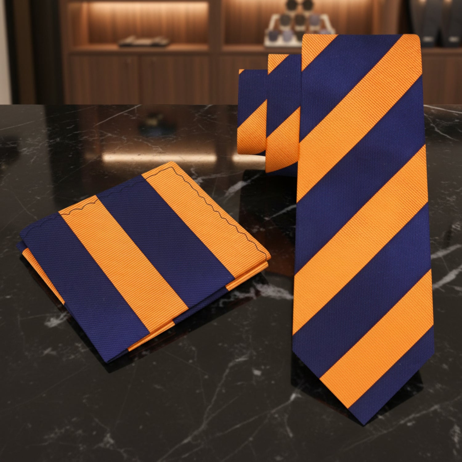 Navy and orange striped tie and pocket square set on a white background