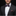 Man wearing a black suit with a patterned bow tie and pocket square on a dark background