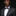 Man wearing a gray suit with a patterned bow tie and pocket square on a black background
