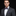 Man wearing a gray suit with a colorful bow tie and pocket square on a black background