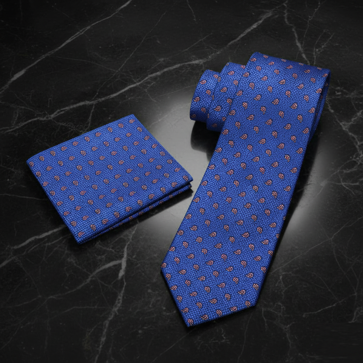 Blue patterned tie and pocket square on a dark marble surface