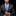 Man wearing a gray suit with a plaid tie against a black background