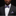 Man wearing a black suit with a blue and pink checkered bow tie and pocket square against a black background
