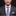 Man wearing a gray suit with a colorful paisley tie and matching pocket square on a black background