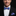 Man wearing a black suit with a blue bow tie and pocket square on a dark background