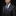 Man wearing a dark gray suit with a blue tie against a black background