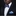 Man wearing a black suit with a white shirt, blue bow tie, and matching pocket square against a black background.