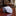 Rolled-up tie with a checkered pattern on a wooden surface, blurred background of a room.