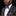 Man wearing a dark suit with a colorful bow tie and pocket square against a black background