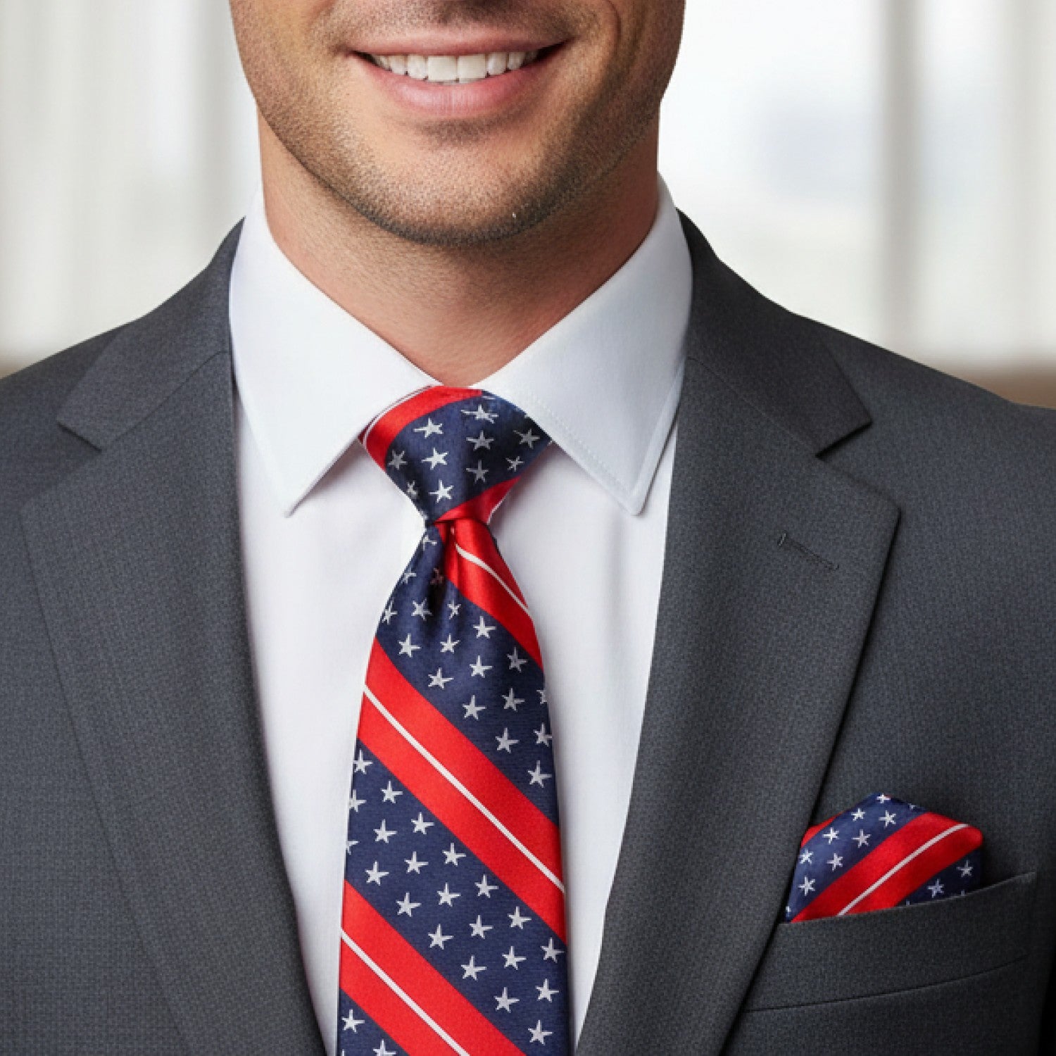 Man wearing a gray suit with a red, white, and blue tie and pocket square.
