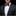 Man wearing a black suit with a colorful bow tie and blue pocket square on a black background