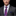Man wearing a gray suit with a colorful paisley tie and pocket square on a black background