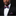 Man wearing a black suit with a red and blue bow tie and pocket square against a dark background
