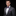 Man wearing a gray suit with a colorful bow tie and pocket square on a black background