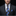 Man wearing a dark suit with a blue and black patterned tie against a black background