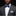 Man wearing a gray suit with a blue bow tie and patterned pocket square on a black background