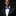 Man wearing a black suit with a blue bow tie and pocket square against a dark background