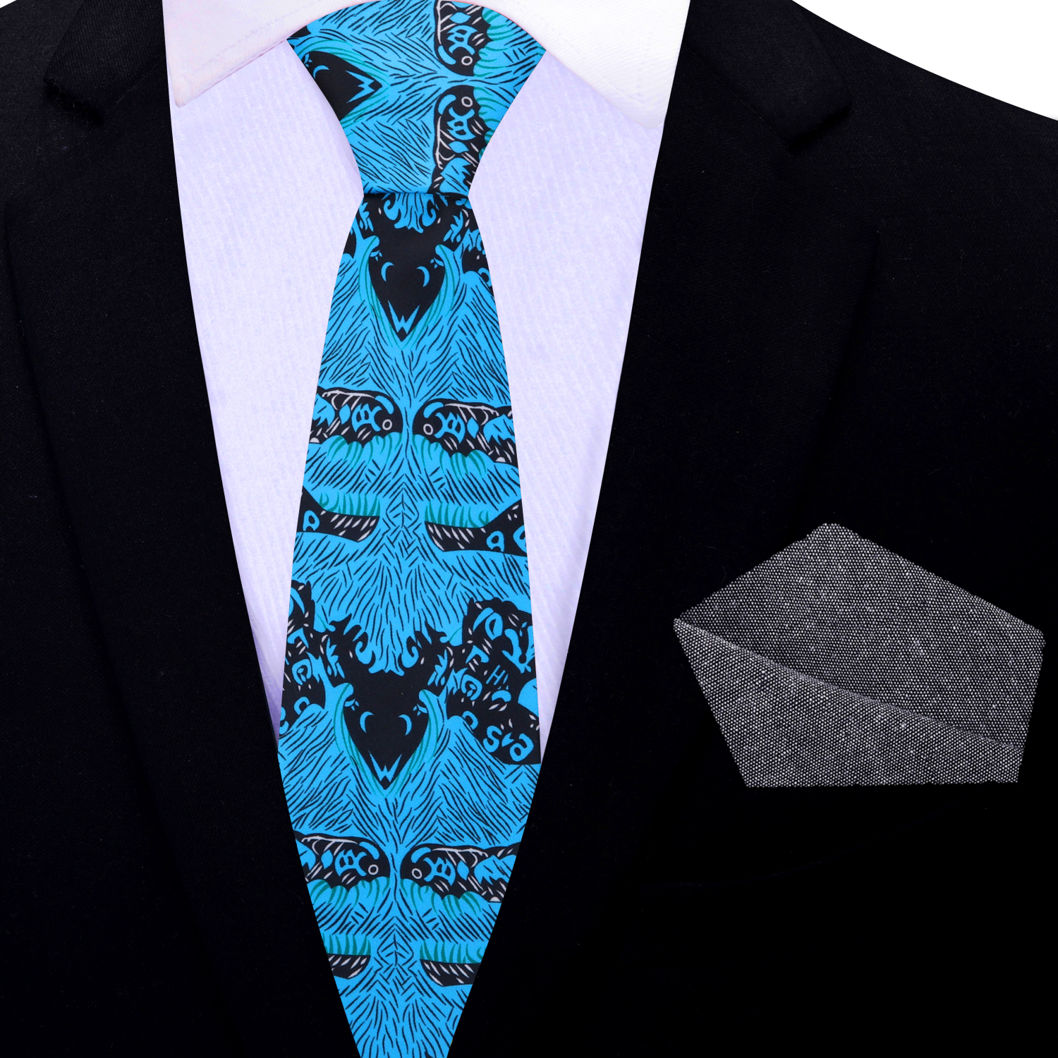 Blue patterned thin tie with black designs on a white shirt with a black jacket, accompanied by a gray pocket square.