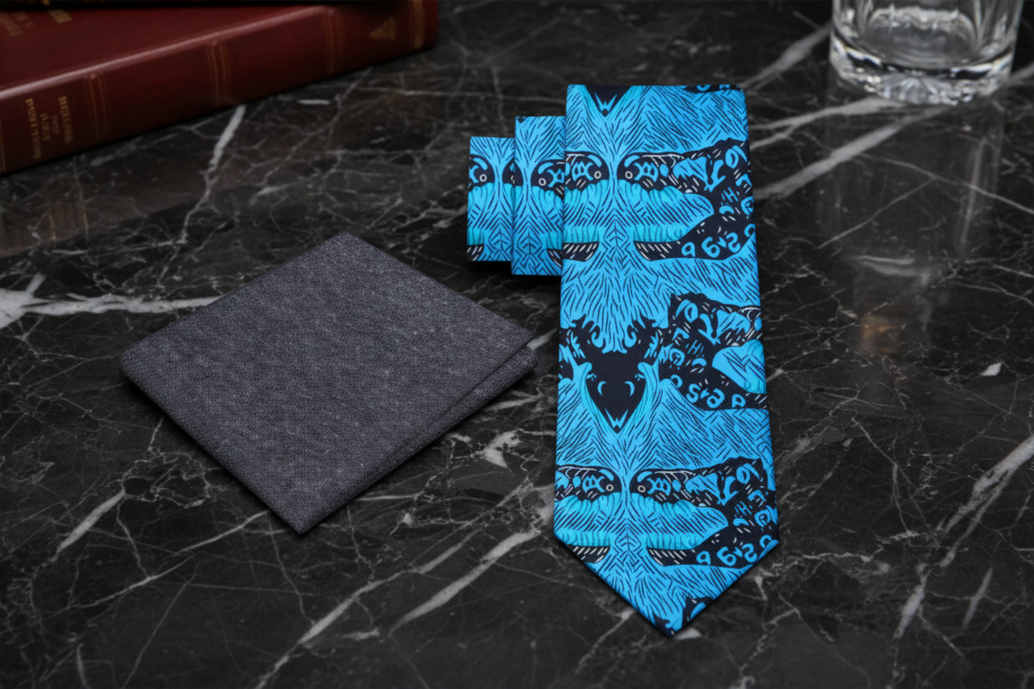 Blue tie with black patterns and gray pocket square on a marble background