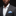 Man wearing a dark suit with a white shirt and blue patterned pocket square on a black background