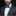 Man wearing a gray suit with a blue bow tie and pocket square on a black background