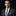 Man wearing a dark suit with a patterned tie and pocket square on a black background