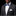 Man wearing a black suit with a white shirt and blue polka dot bow tie on a black background