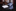 Blue and white patterned tie and silver pocket square on a dark surface with a blurred background