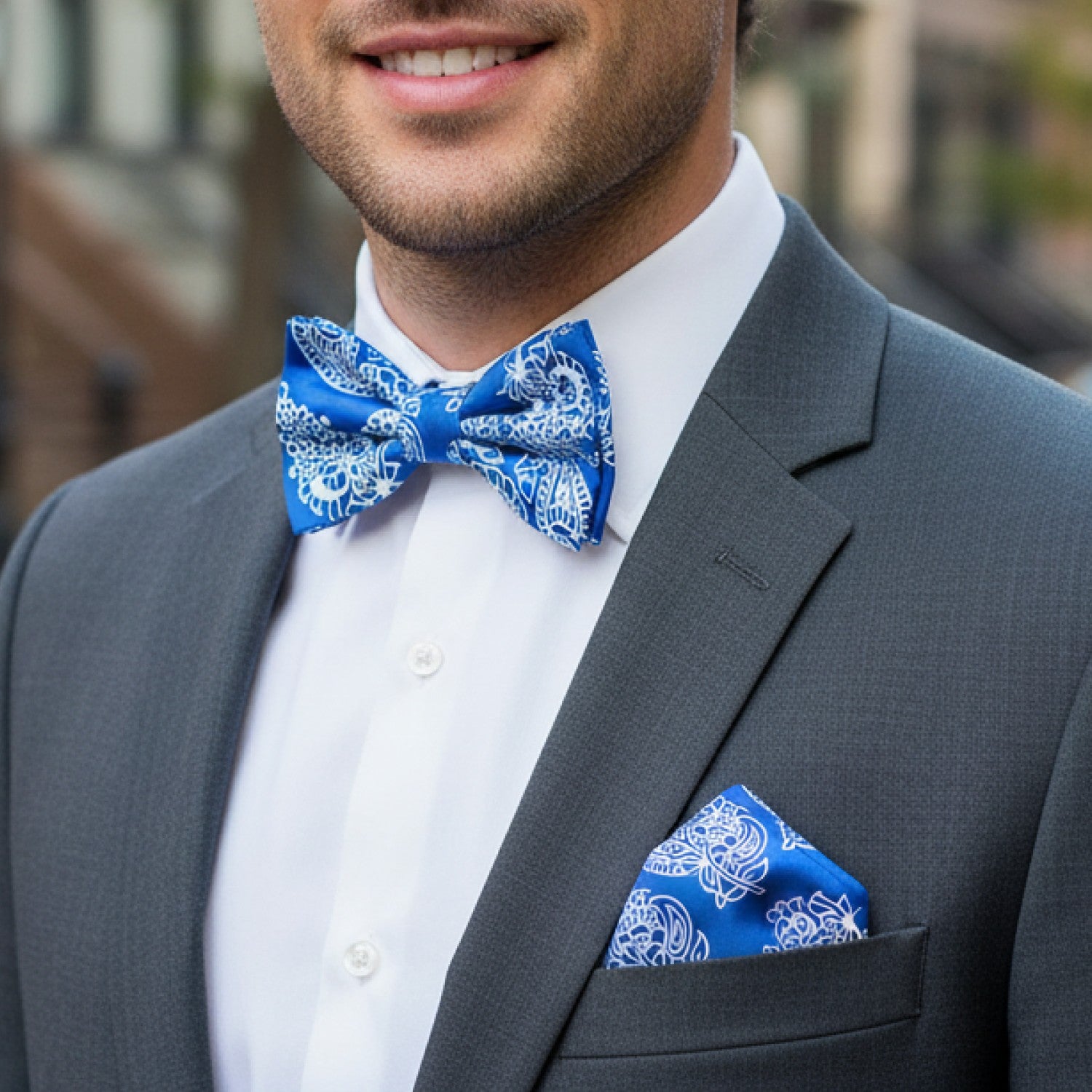 Man wearing a gray suit with a blue patterned bow tie and pocket square.