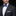 Man wearing a black suit with a blue patterned bow tie on a black background