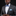 Man wearing a gray suit with a blue bow tie and pocket square on a black background