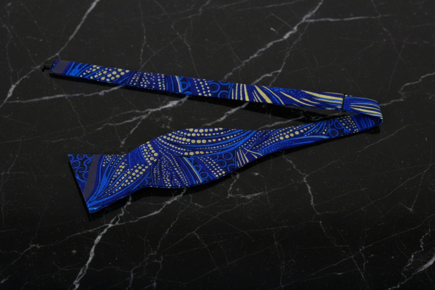 A blue, black, and yellow bow tie with a floral 'Tulips at Midnight' pattern 