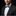 Man wearing a black suit with a blue patterned bow tie and matching pocket square on a black background
