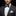 Man wearing a dark suit with a patterned bow tie and striped pocket square on a black background