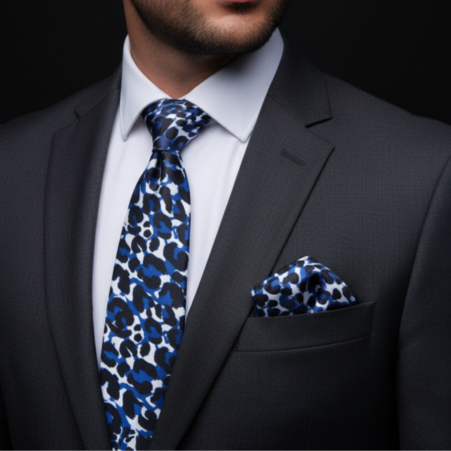 A man wearing a white, blue, black cheetah necktie and square with nice suit