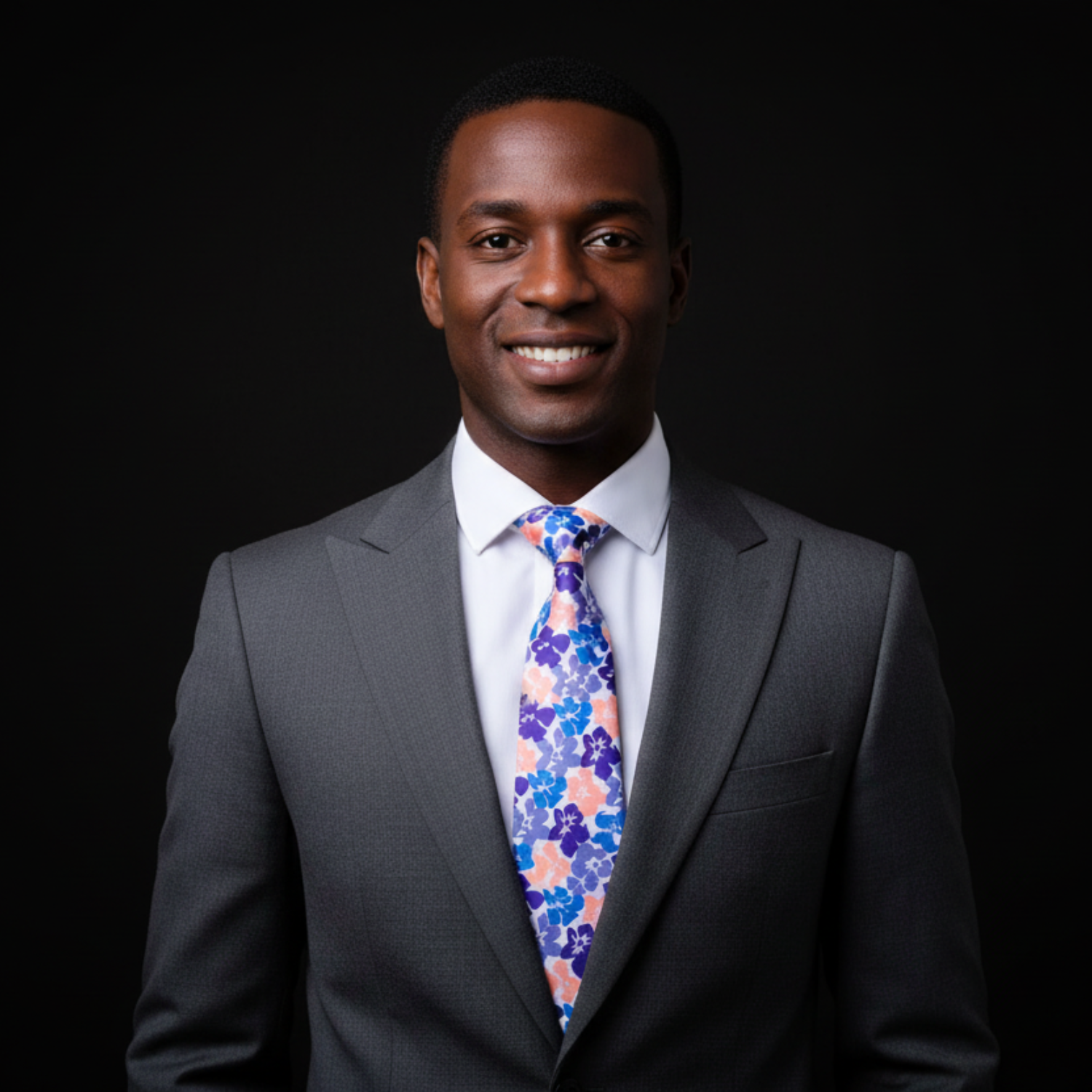 Man wearing a gray suit with a colorful floral tie on a black background
