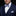 Man wearing a navy suit with a patterned bow tie and pocket square on a black background